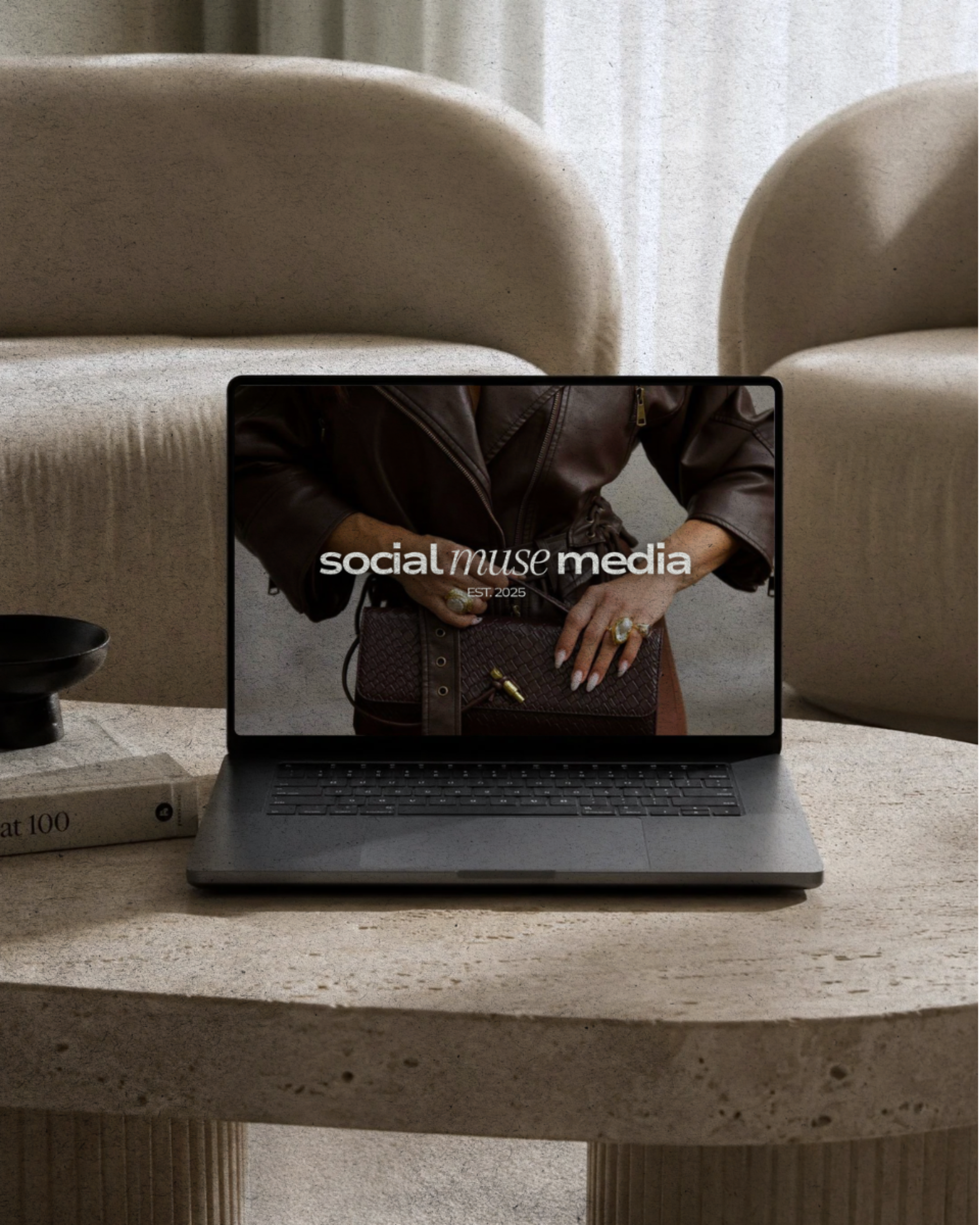 A laptop on a stone table displaying a fashion model wearing jewelry, with stone chairs in the background.