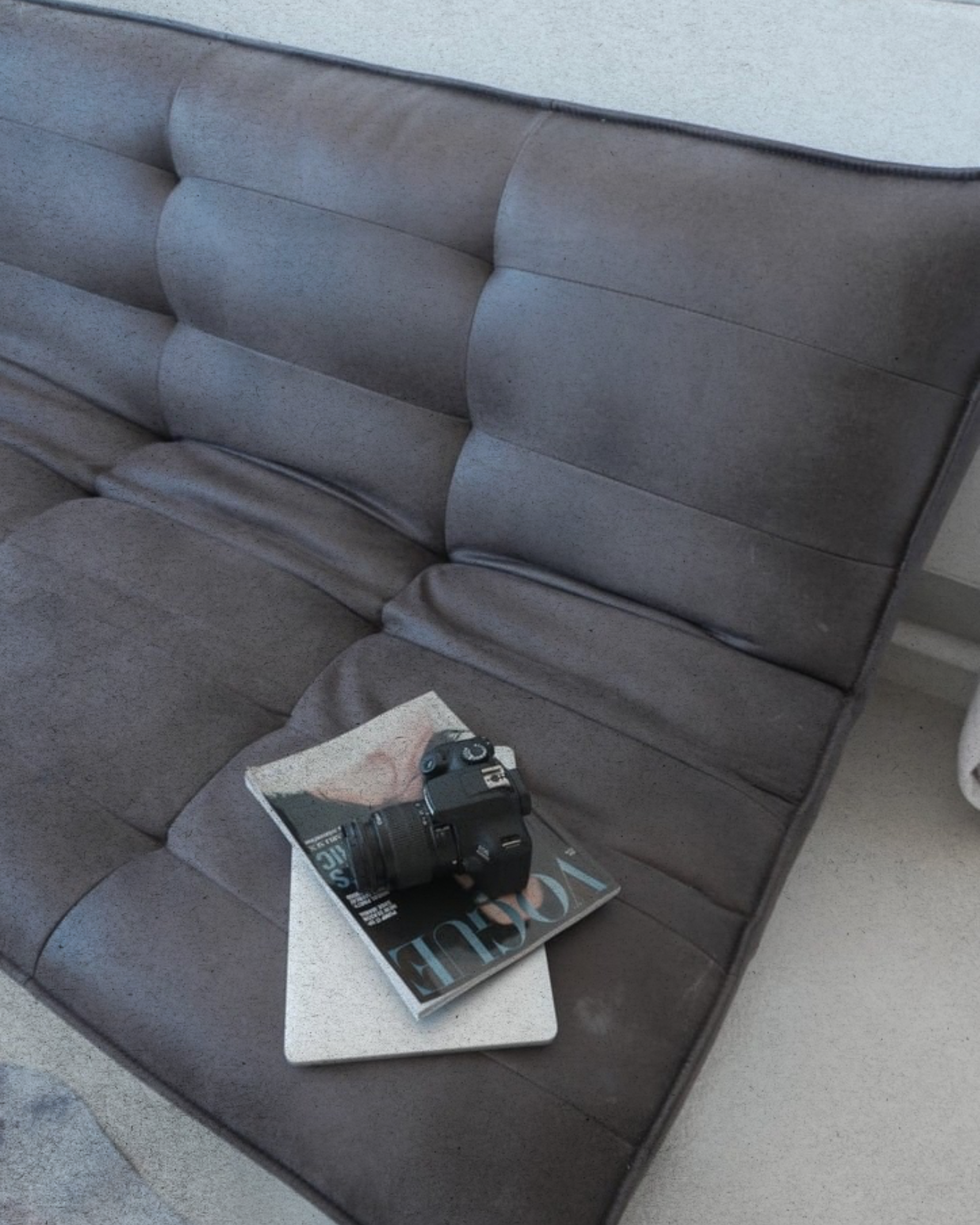 Close-up of a silver upholstered headboard or panel with a black camera and a Rolling Stone magazine placed on it.