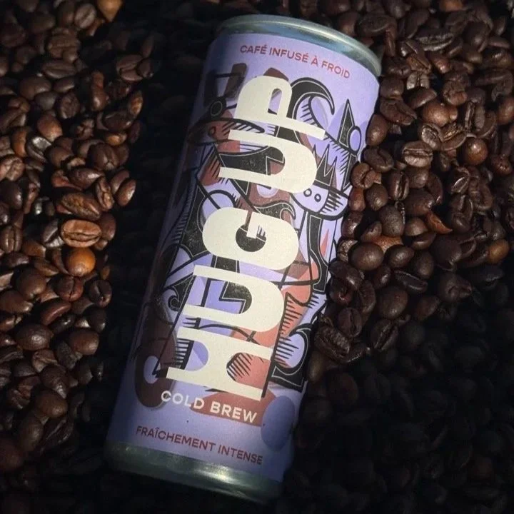 Canette de café infusé à froid, entourée de grains de café.