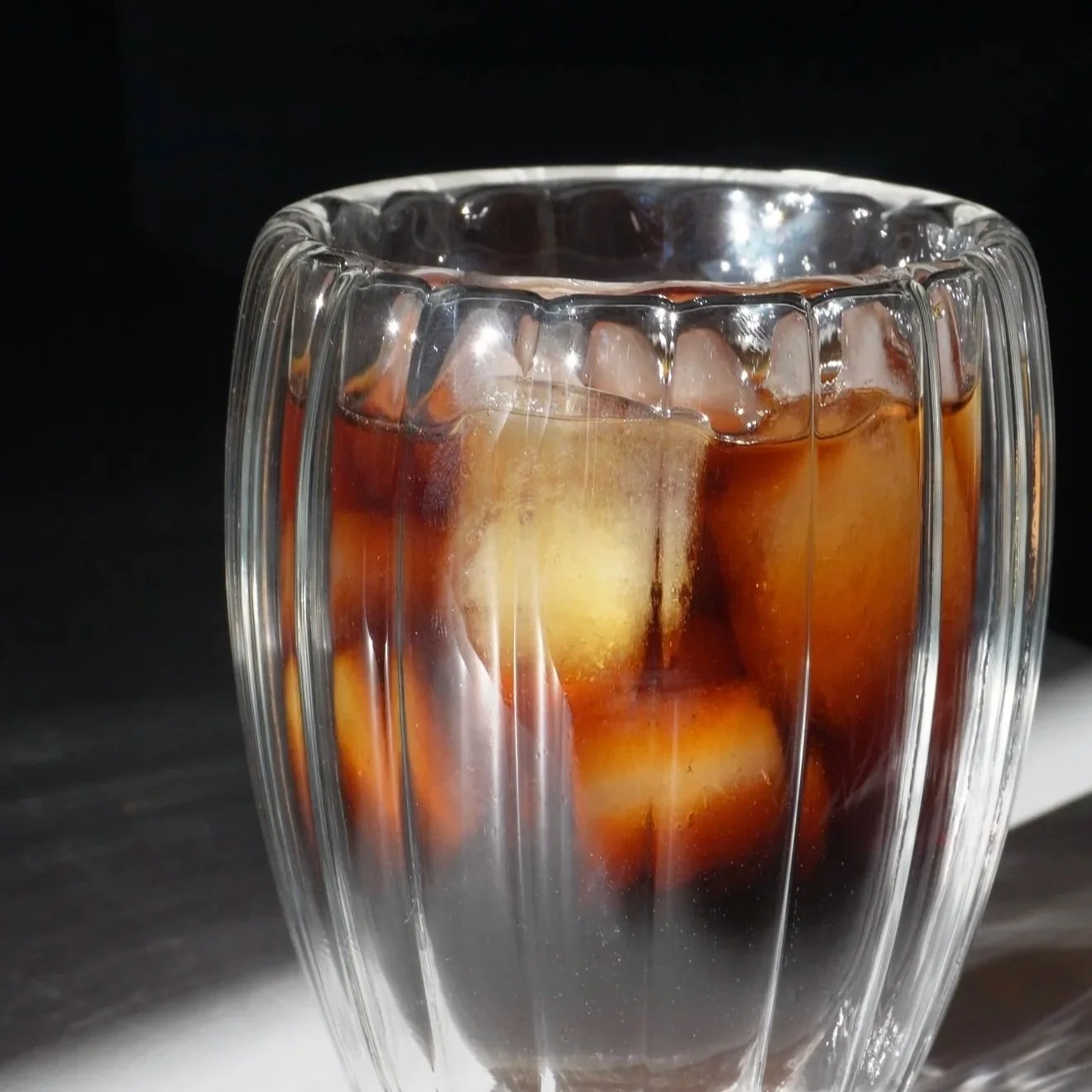 Verre en verre avec glaçons et une boisson sombre, peut-être du cola.