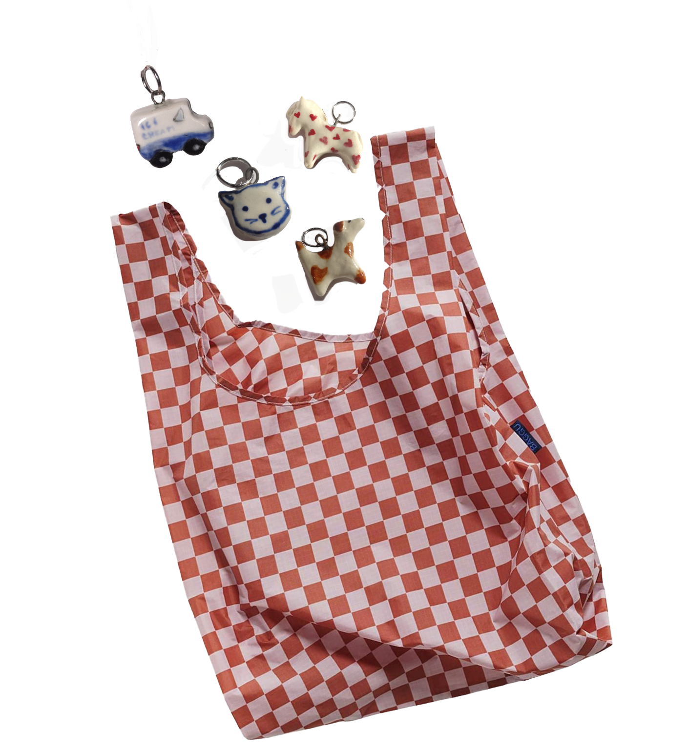 A red and white checkered reusable shopping bag hanging on a hook with four small charm keychains of a bus, a cat, and two stars, attached to the bag's handle.
