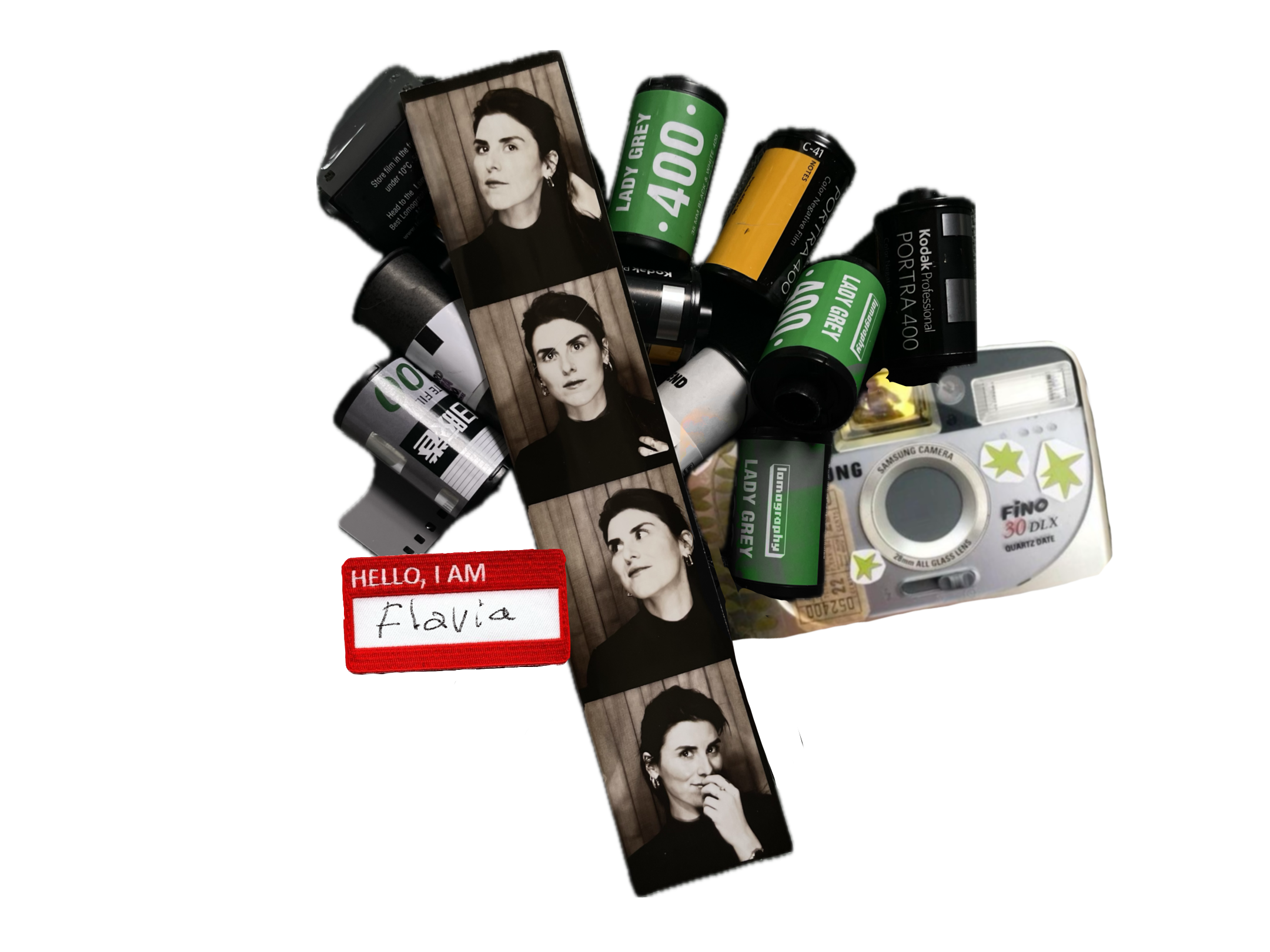 Collection of film canisters, strip of black and white photographs of a woman, a white compact camera with star stickers, and a red name badge that reads "Hello, I am Flavia".