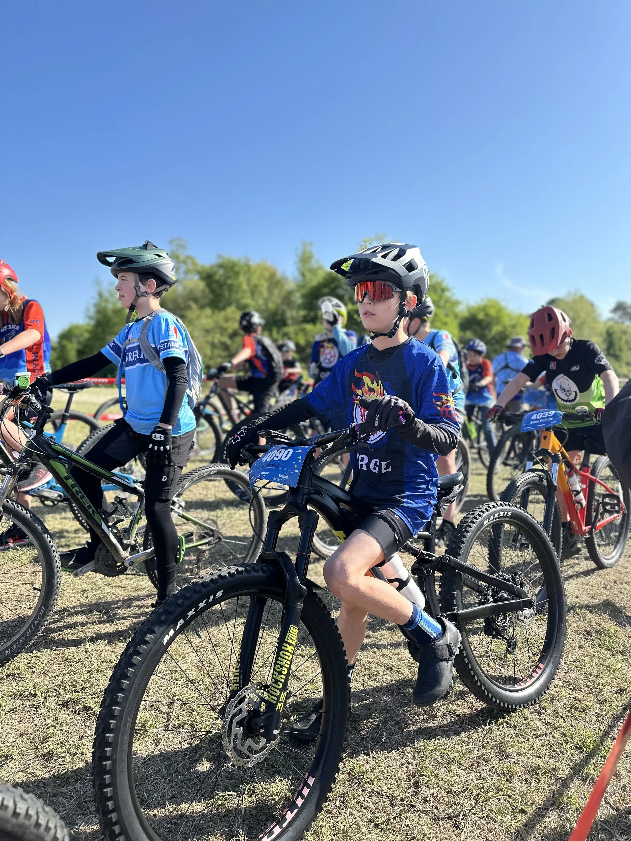 Children in cycling gear participating in a bike race outdoors on a sunny day.