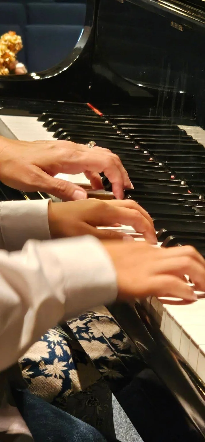 Students’ hands playing a grand piano during a recital