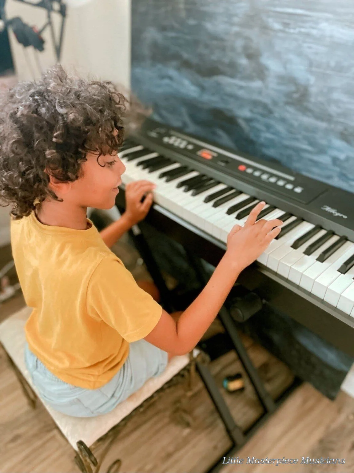 Young piano student practicing at a keyboard in Little Masterpiece Musicians Studio.