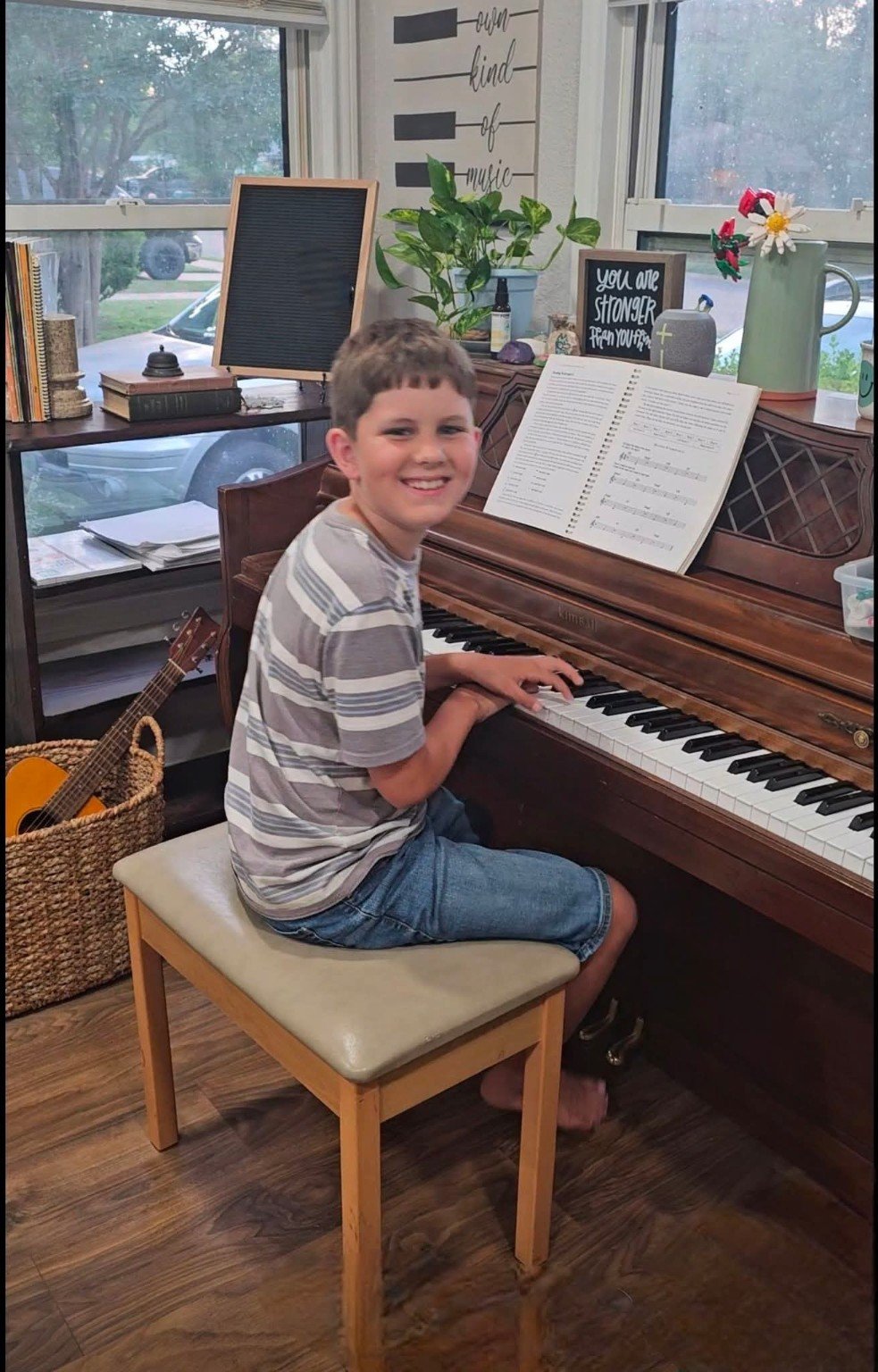 Young piano student seated at the keyboard preparing to perform.