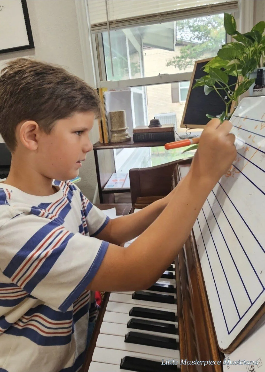 Piano student writing music notes during a Little Masterpiece Musicians Studio lesson.