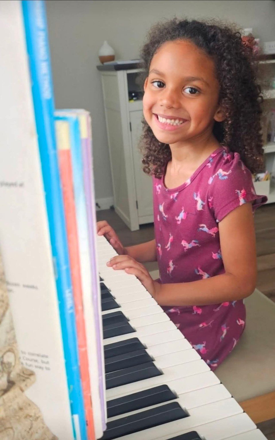 Smiling young piano student seated at the keyboard.