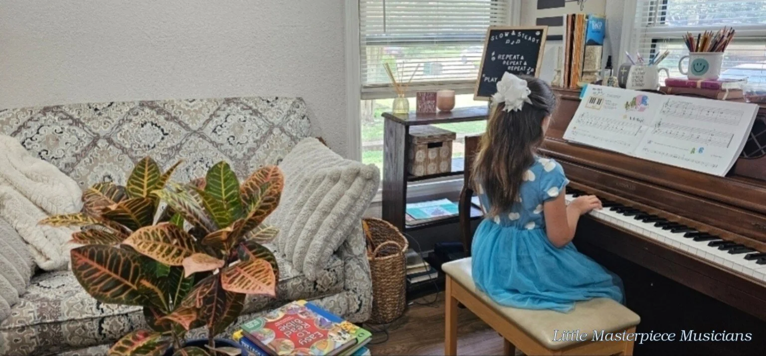 Young piano student in a blue dress practicing at the studio piano.