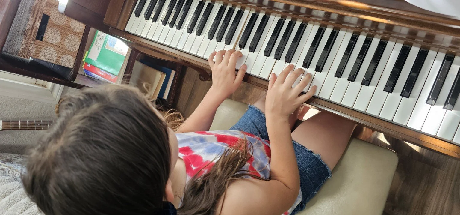 Student hands practicing at an upright piano