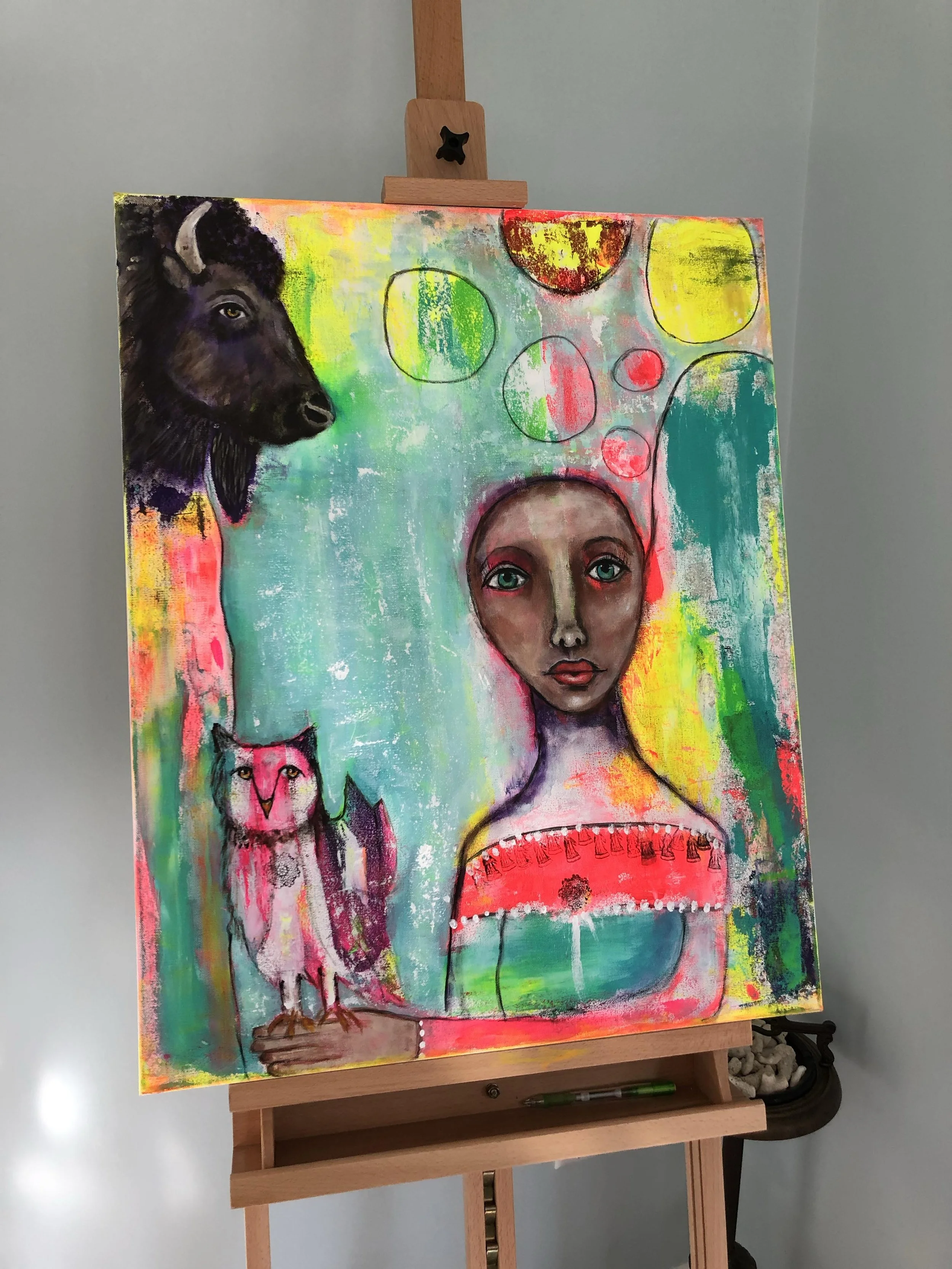 Colorful abstract painting featuring a woman's face, a goat's head on the upper left, an owl on the bottom left, and various colorful circular shapes.