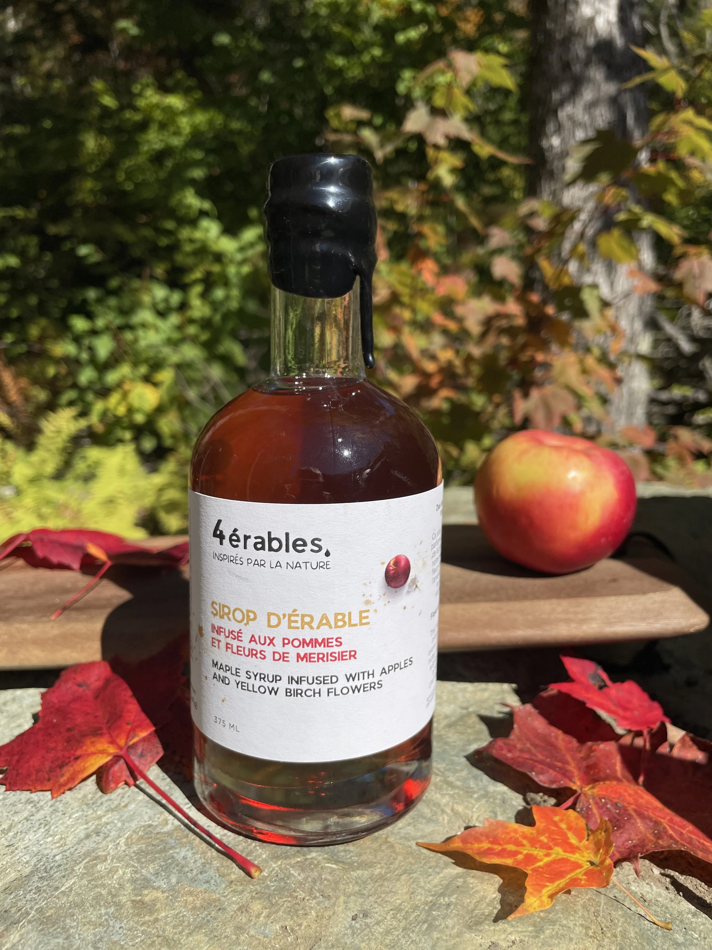Sirop d'érable pommes et fleurs de merisier , bouteille de verre scellée de cire sur fond de feuillage automnal, de l'érablière Les 4 érables