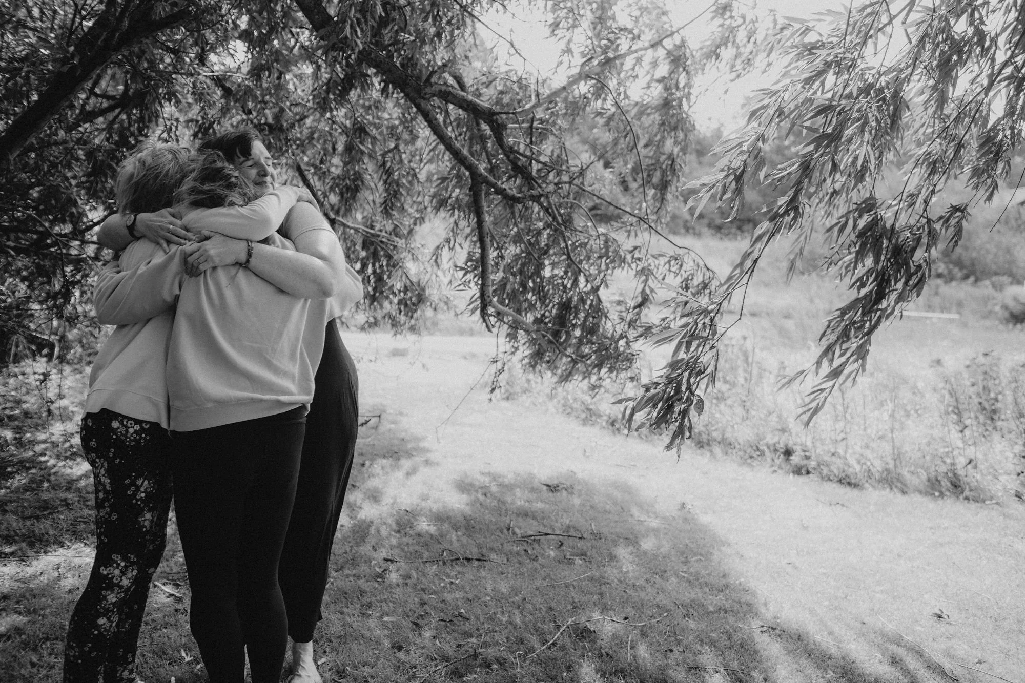 3 women hugging under willow tree