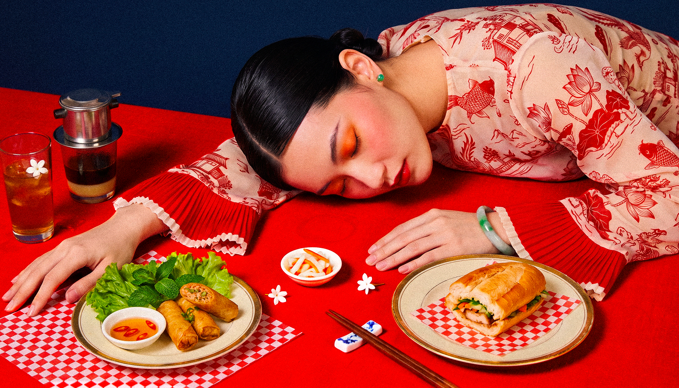 Model resting on a red table set with a bánh mì, spring rolls, pickled vegetables, Vietnamese drip coffee and iced tea, Pham's Bánh Mì catering in Montreal