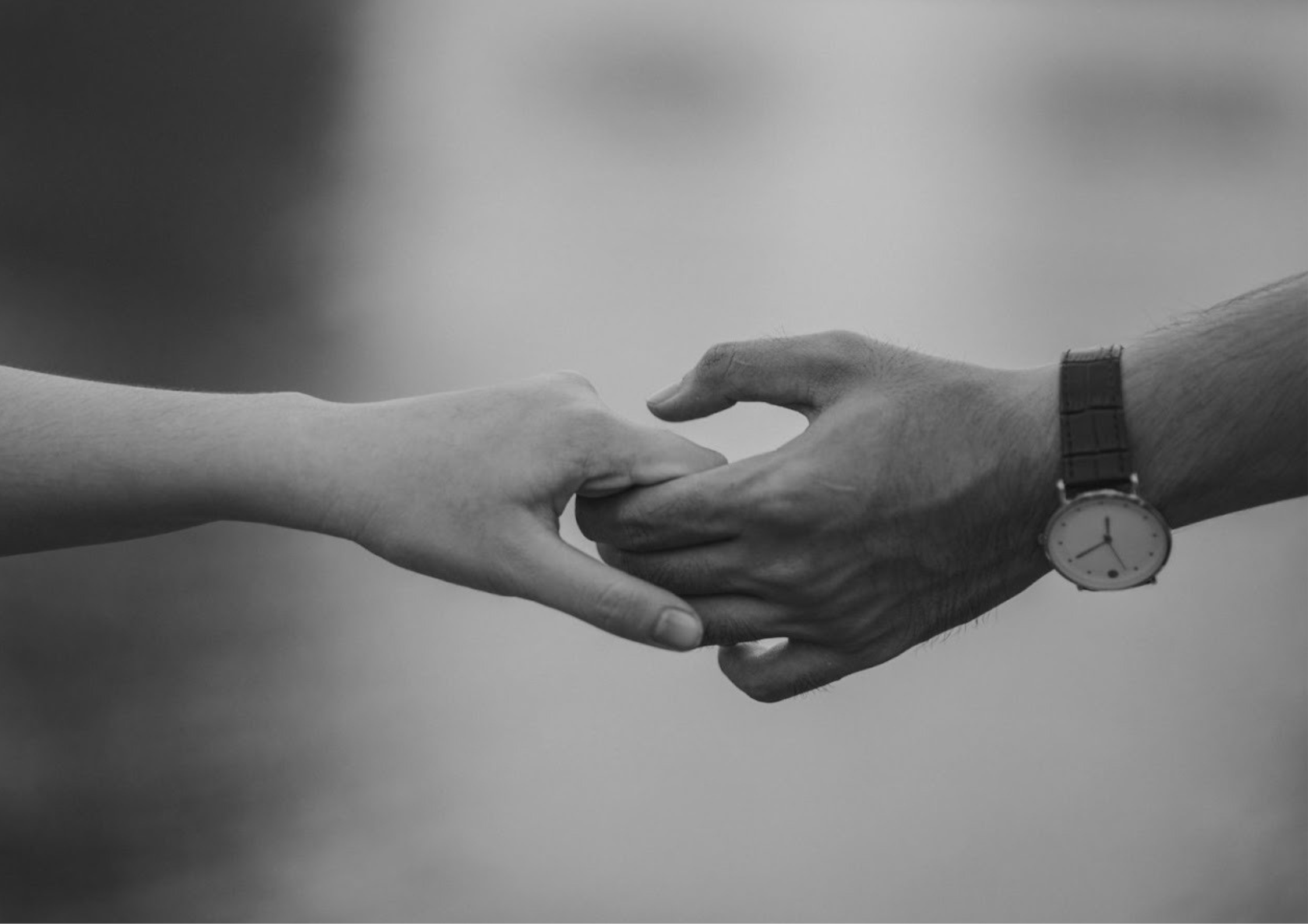 Close-up black-and-white image of two hands holding gently, representing reassurance, connection, and the emotional grounding needed when healing anxious attachment.