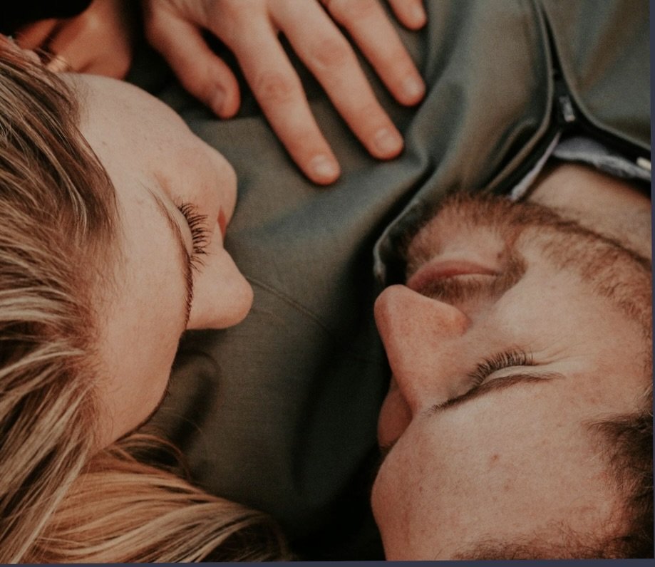 Close-up of a couple lying down facing each other, with the woman on the left and the man on the right, sharing an intimate moment. Their love is all-encompassing, but perhaps smothering or unhealthy.