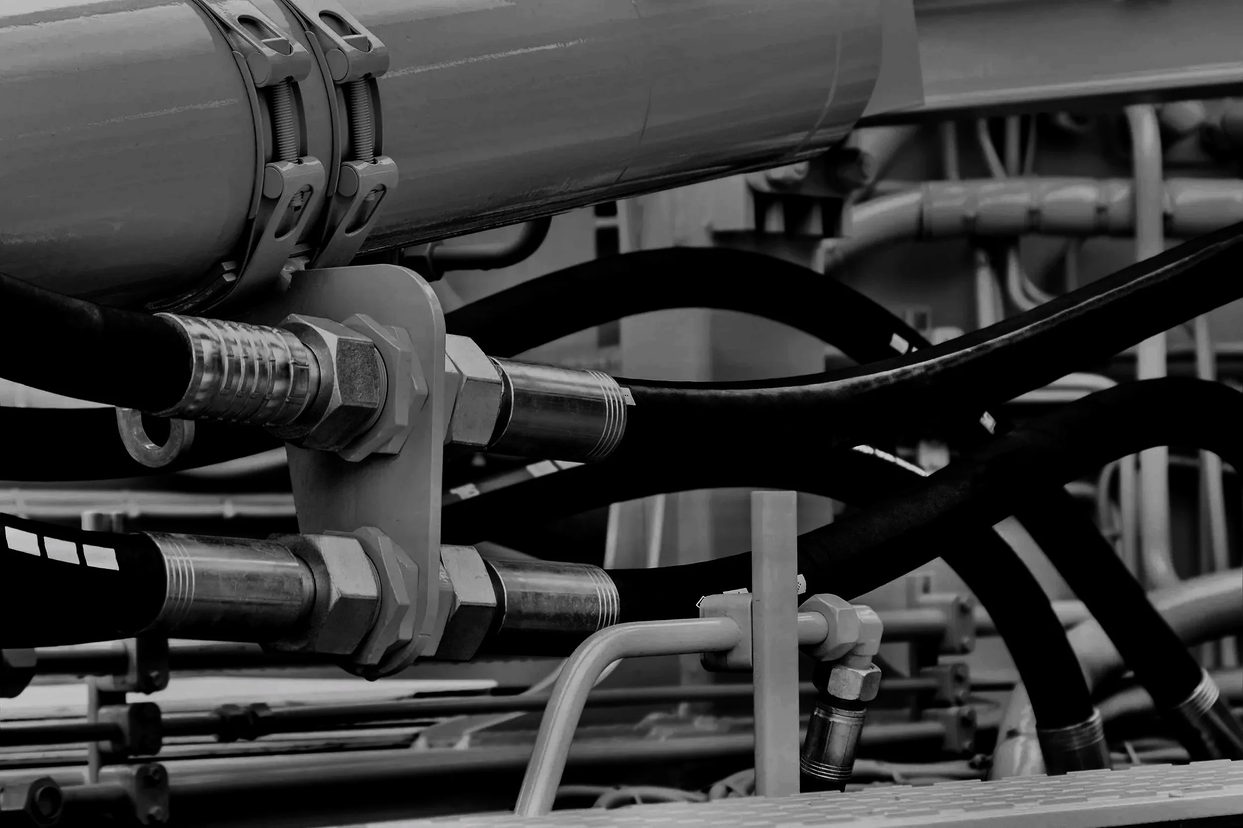 Close-up of industrial pipes and fittings in black and white.
