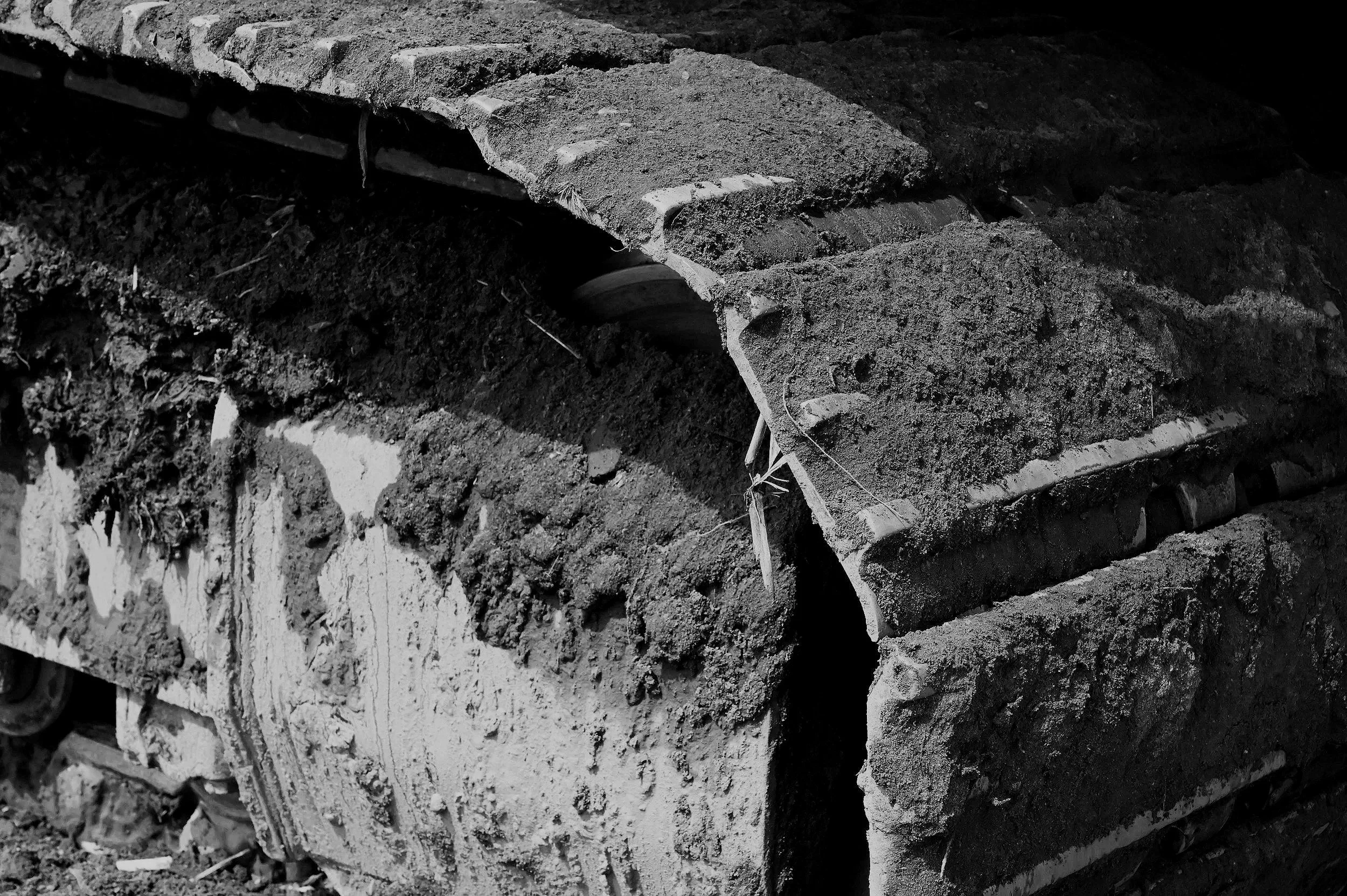 Close-up of a damaged construction vehicle tracked wheel covered in mud and dirt.