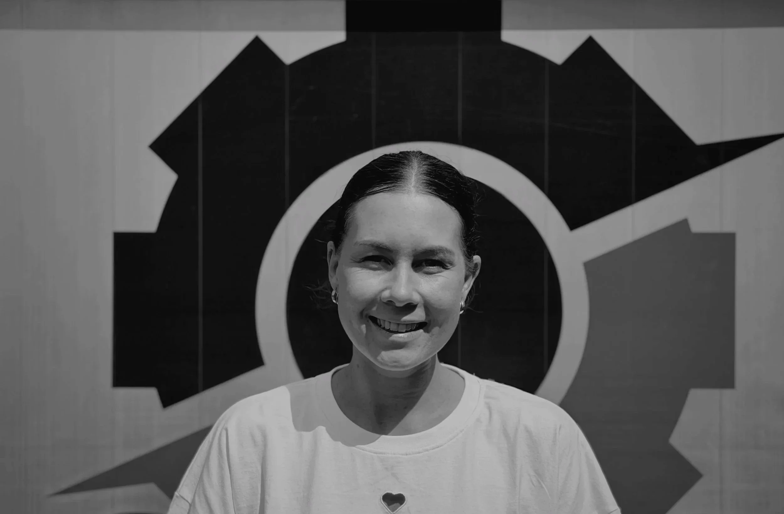 Black and white photo of a woman smiling in front of a geometric background.