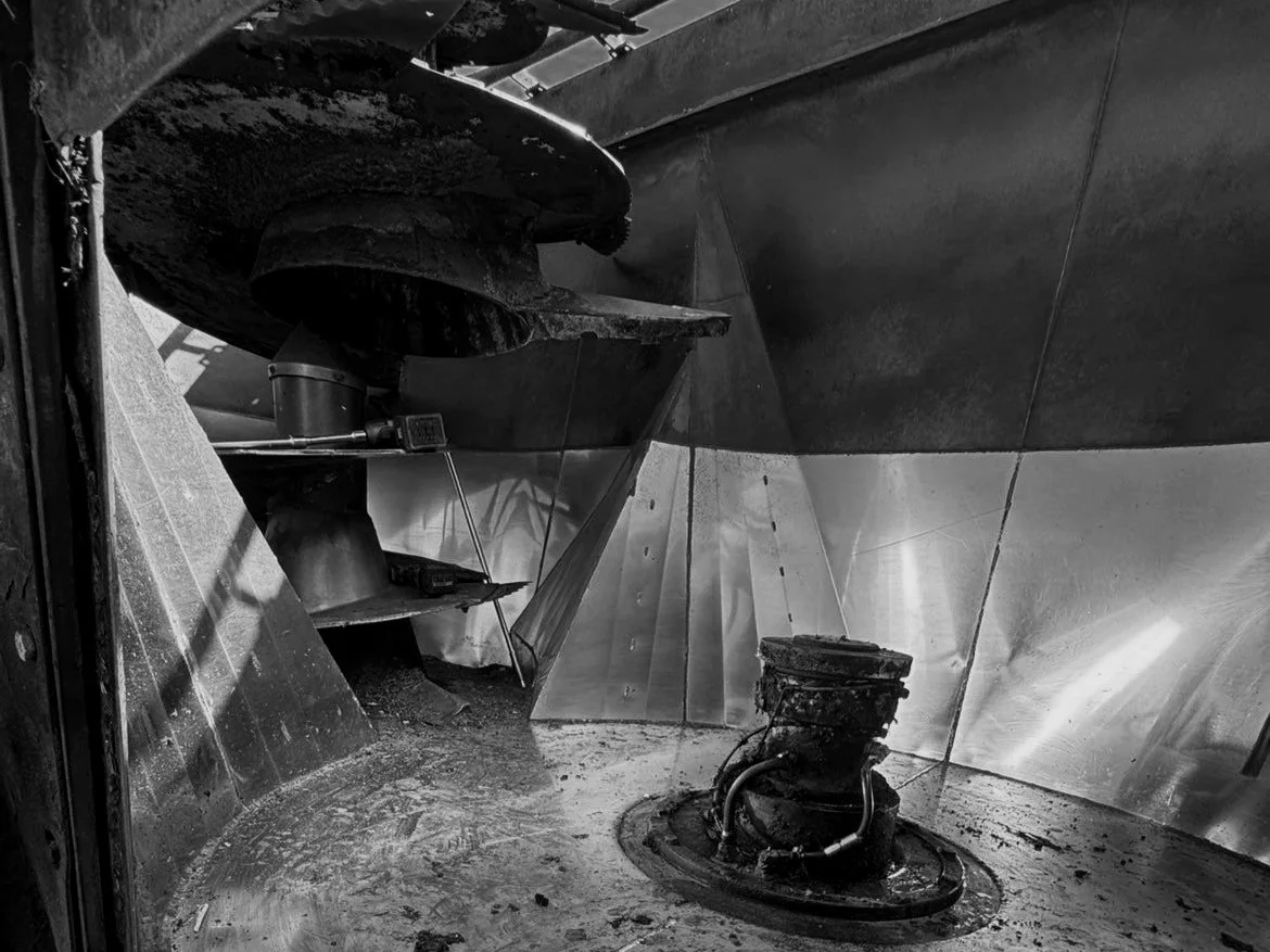 Close-up of the interior of a submarine or underwater vessel showing bulkheads and mechanical equipment, with dirt and grime on the floor and equipment.