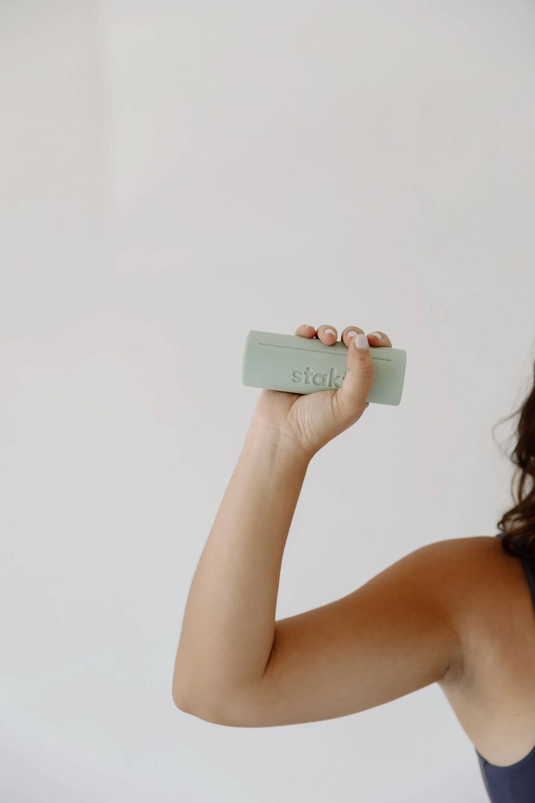 A person in a pilates class holding a light blue dumbbell.