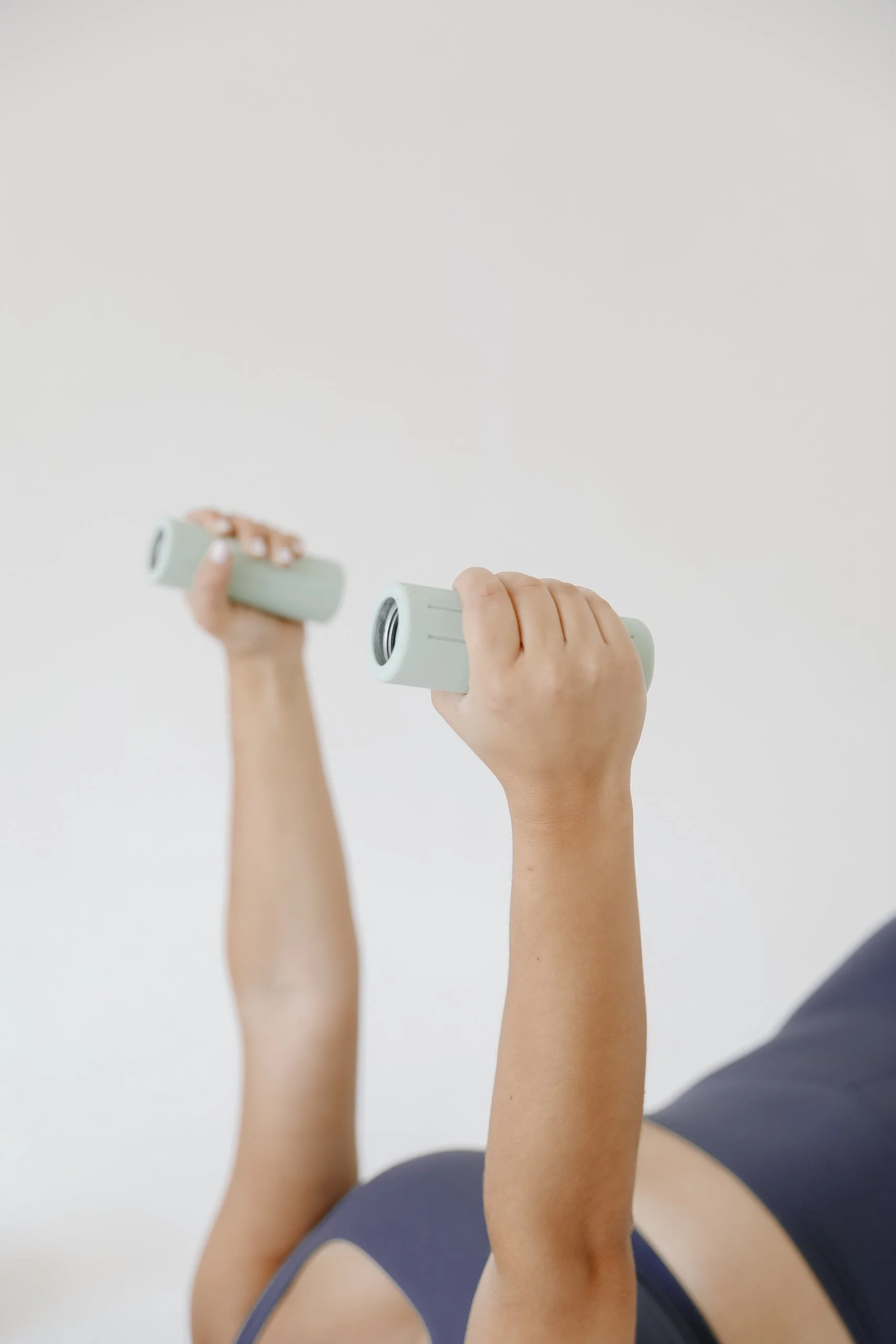 Person holding small dumbbells and exercising in a pilates class.