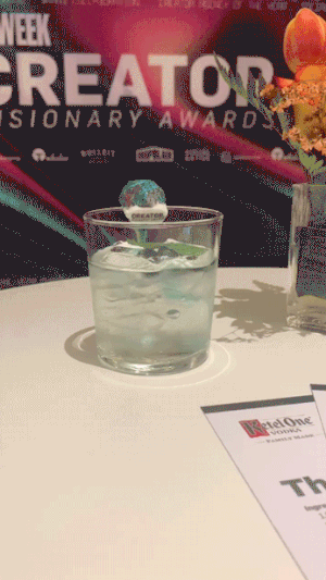 A glass of water with a blue marble inside, on a table at an event or award ceremony