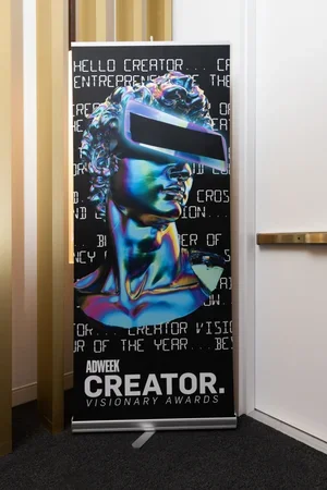 A promotional banner featuring a colorful digital illustration of a person's head wearing virtual reality goggles, with a black background and white text promoting the Adweek Creator Visionary Awards.