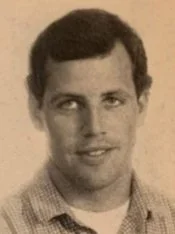 Black and white portrait of a young man with dark hair, wearing a collared shirt.