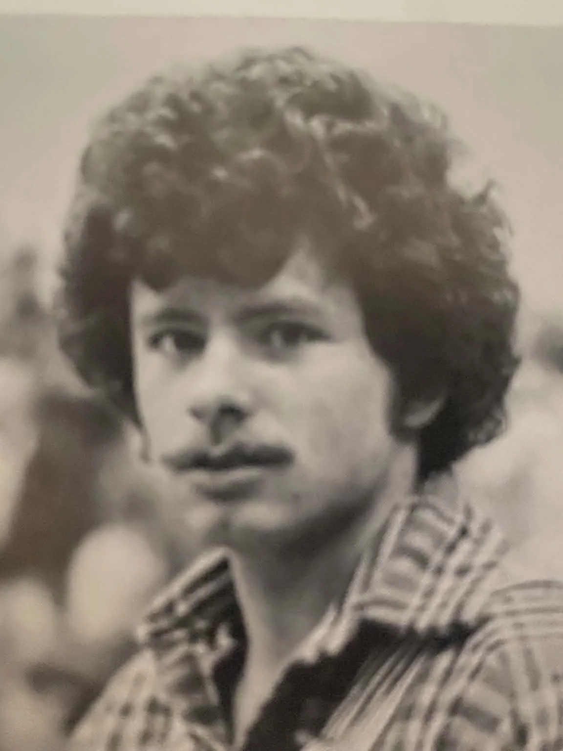 Black and white photo of a young woman with short curly hair, wearing a vertically striped shirt, looking directly at the camera.