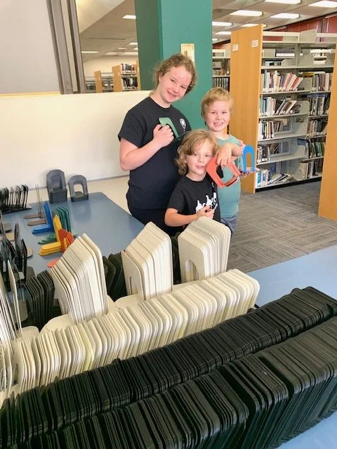 Three kids in a library browsing the maze of plastic number tiles.