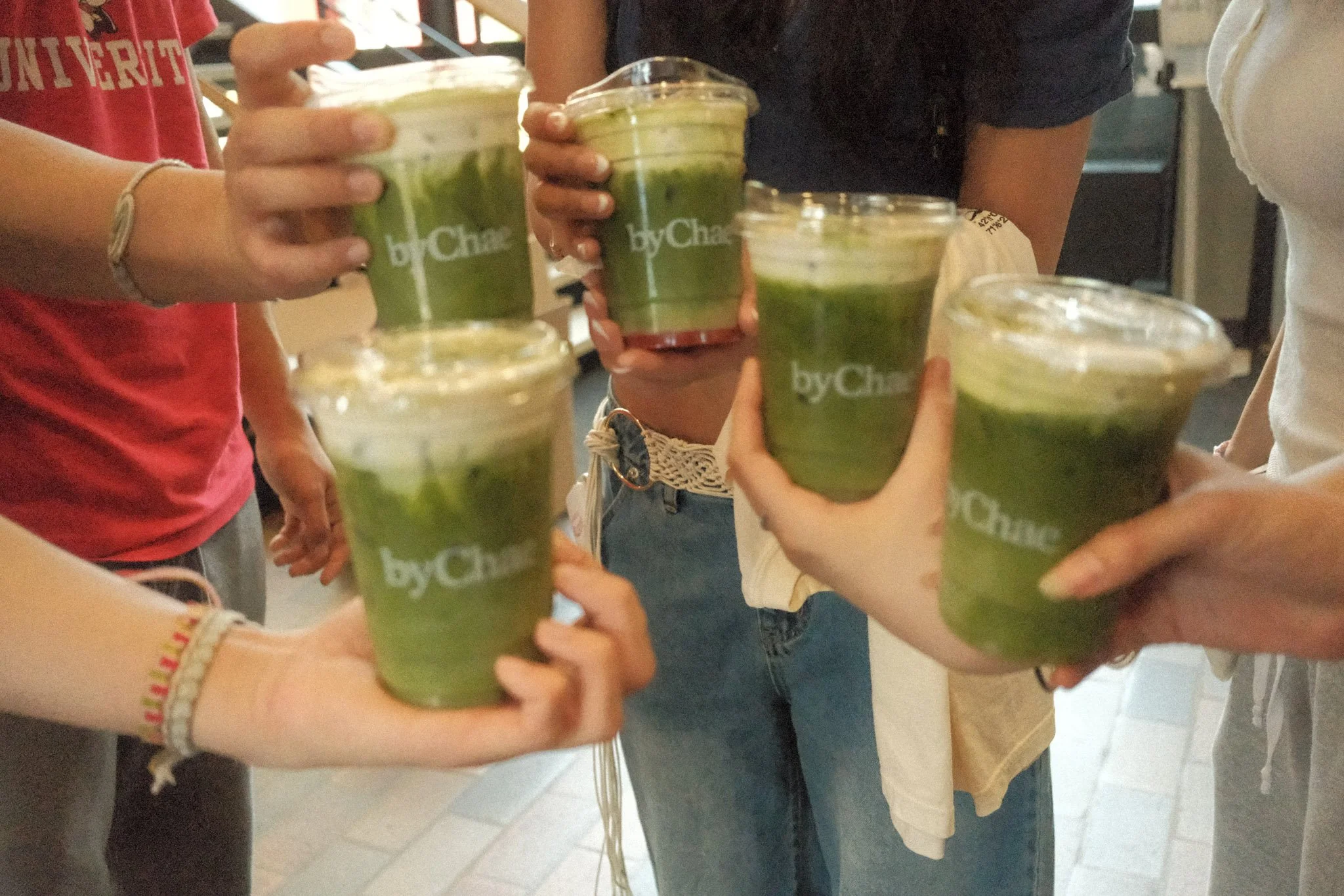 Group of people holding cups of green smoothie in a social setting.