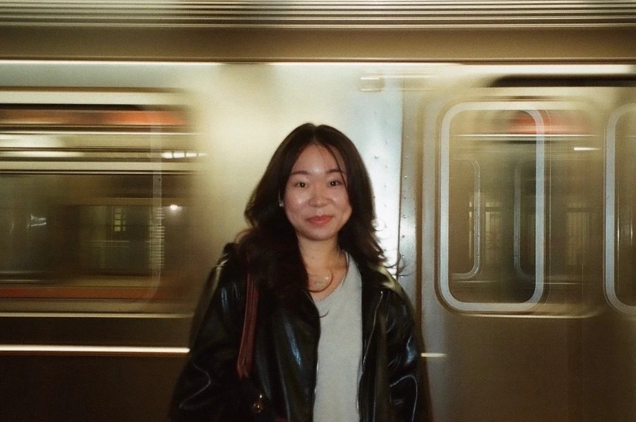 A woman standing in front of a moving train at a subway station.