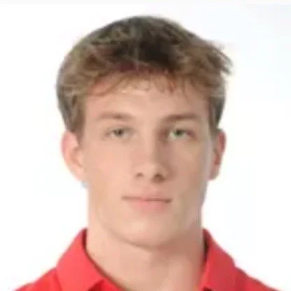 Portrait of a young man with light brown hair wearing a red shirt, looking at the camera with a neutral expression.