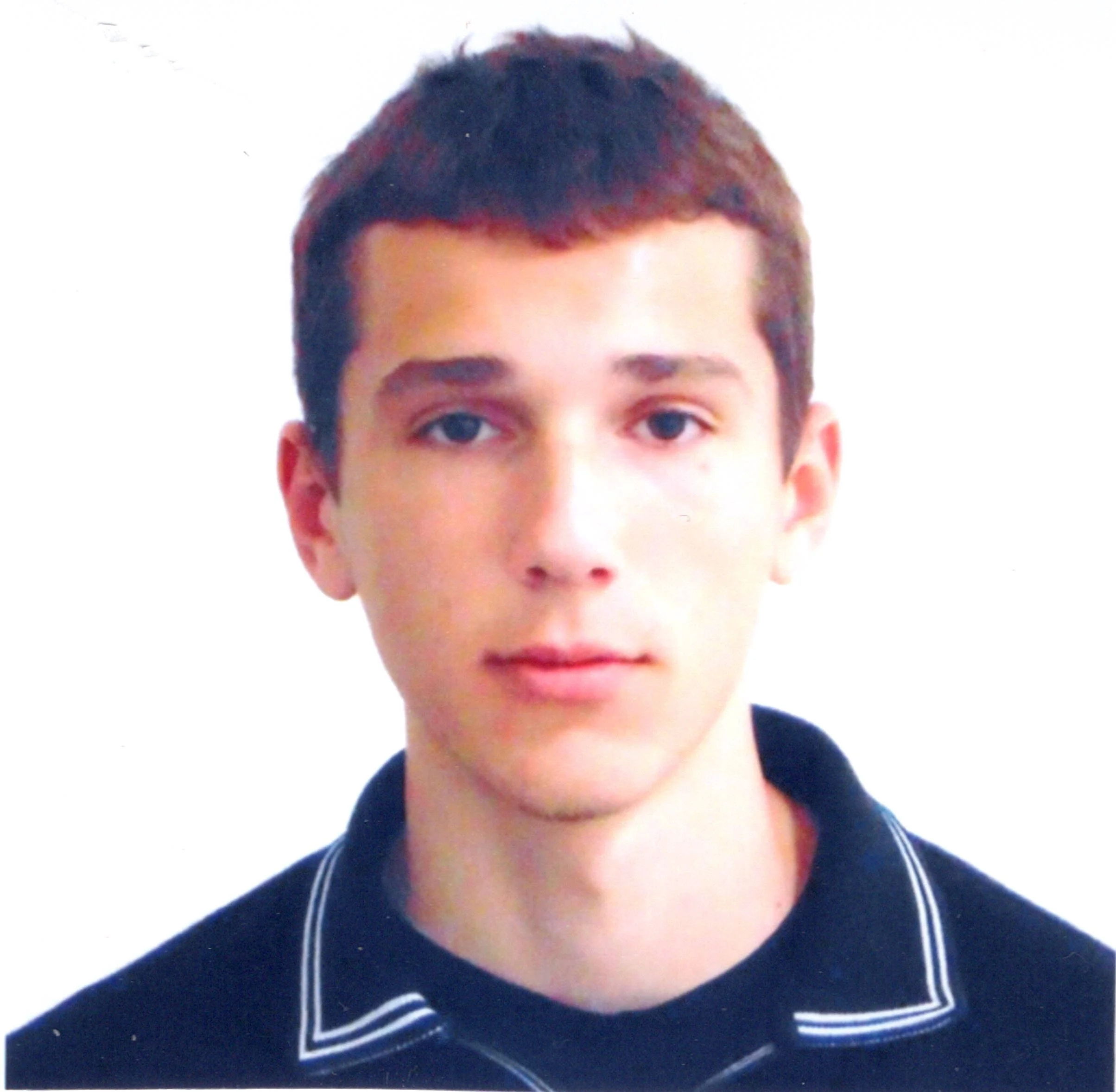 Partial view of a young person's face with short brown hair, blue eyes, wearing a dark shirt with white stripes, and white earphones.