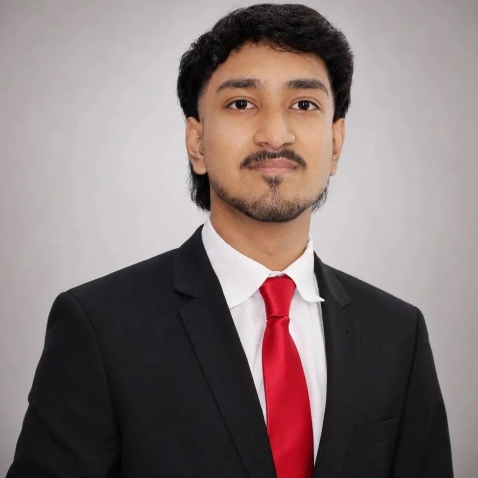 A man in a black suit with a white shirt and red tie, posing for a professional photo.