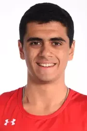Headshot of a young man with short dark hair, smiling, wearing a red Under Armour shirt against a white background.