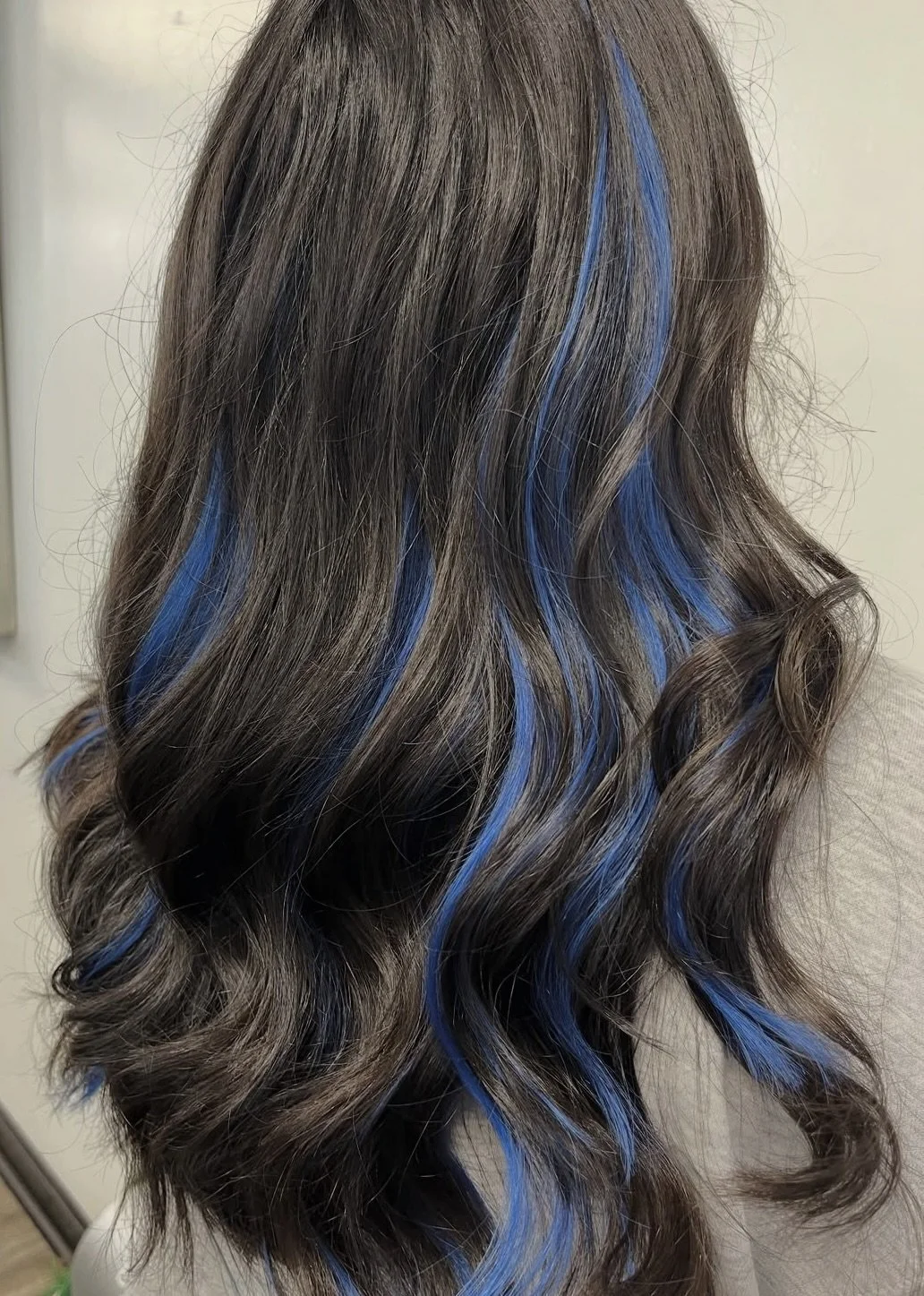 Wavy, brunette hair with blue highlights.