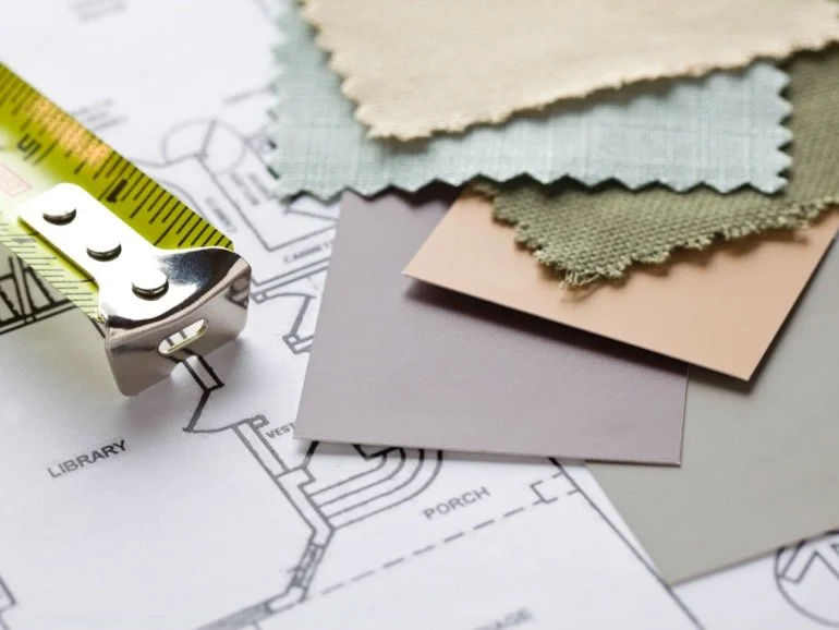 Sample interior design materials, including fabric swatches, paint samples, tape measure, and a floor plan.
