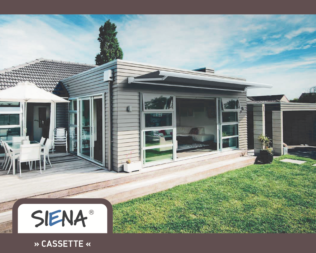 A modern house with large glass sliding doors opening onto a wooden deck, outdoor furniture, and a backyard with green grass and a small tree in a planter. The house has grey siding and a retractable awning.
