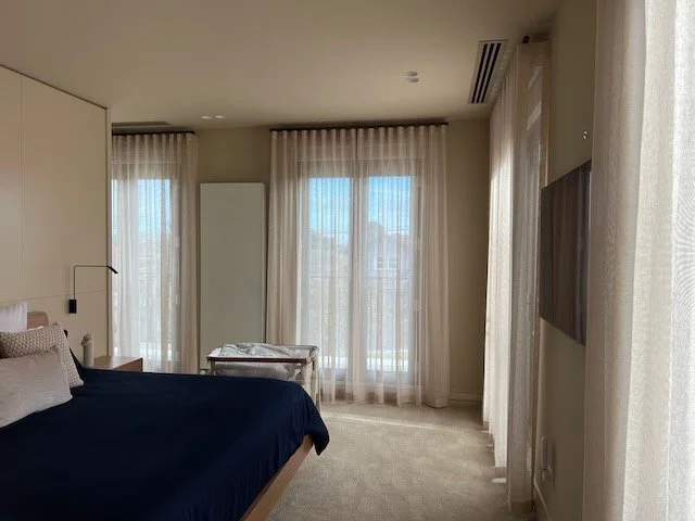Floor-length sheer curtains by Evans Curtains and Blinds installed across multiple bedroom windows, allowing soft natural light into the room.