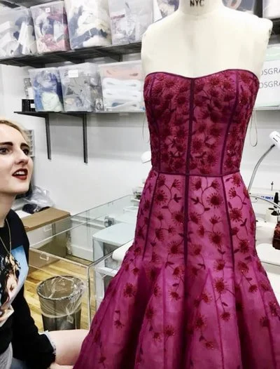 A dress displayed on a mannequin, featuring a strapless, fitted bodice with a floral pattern and a full skirt, in a sewing or fabric store setting.