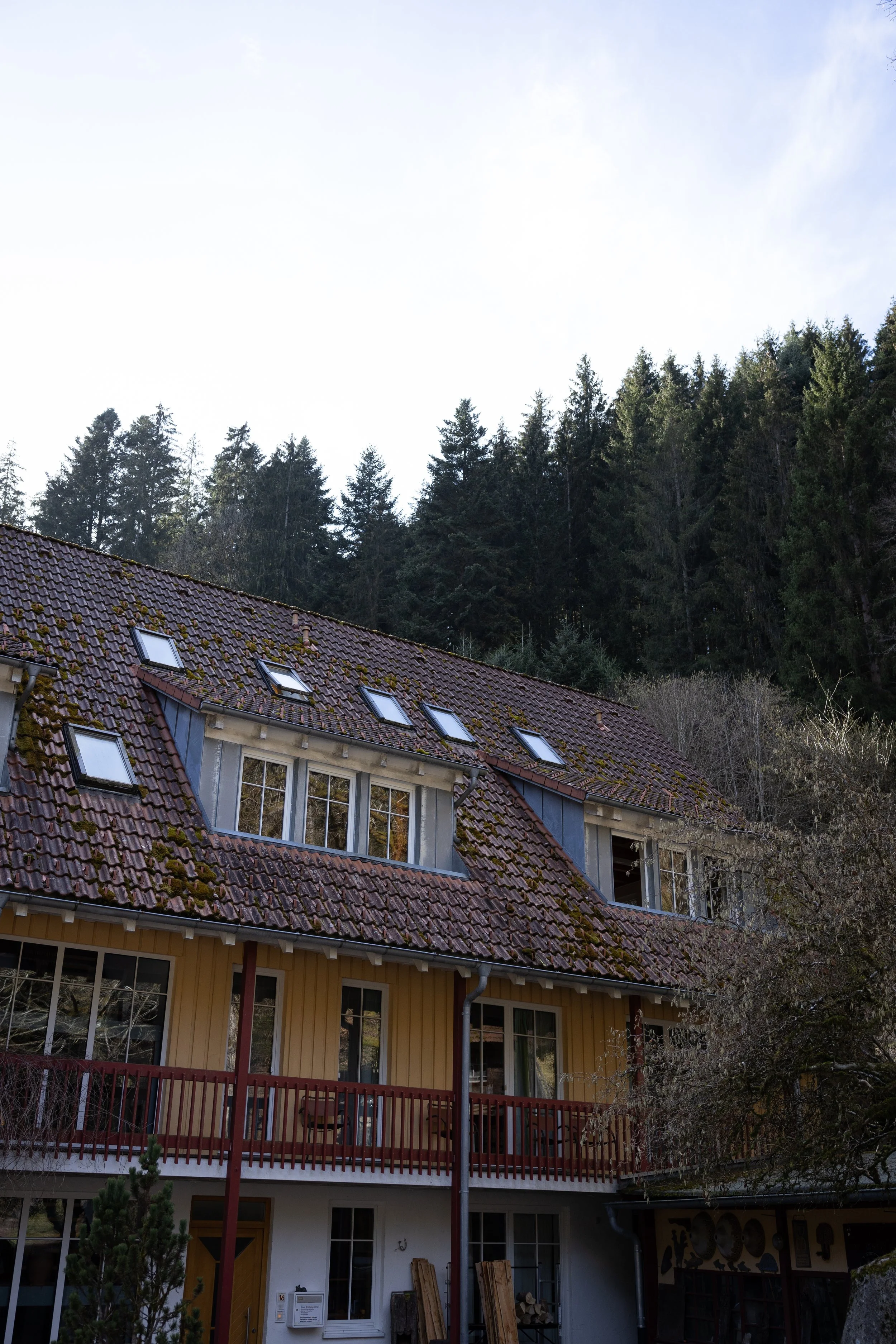 Unser Seminarhaus im Schwarzwald mit einem Ziegeldach vor einem bewaldeten Hügel