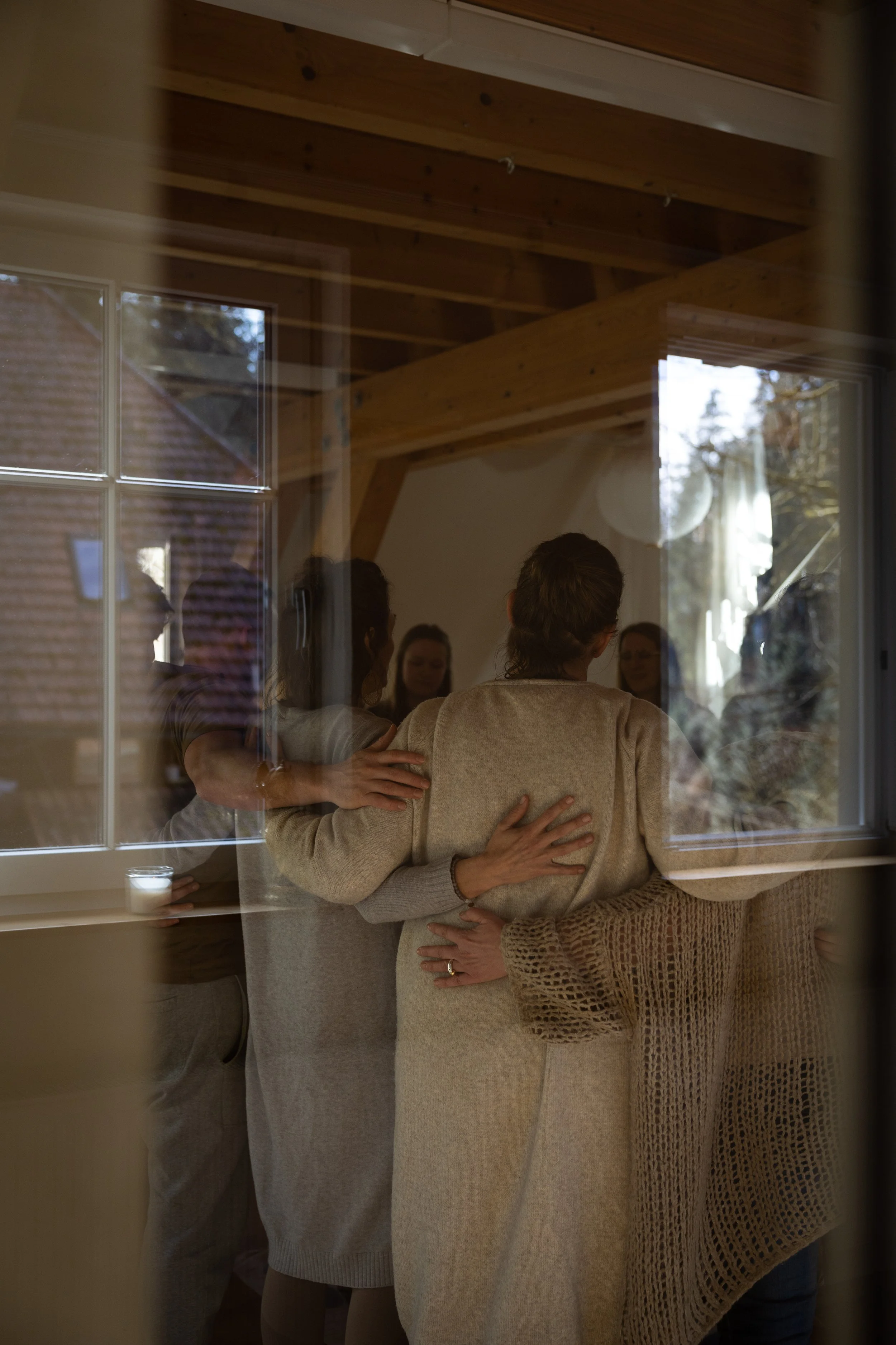 Menschen, die sich umarmen, sichtbar durch ein Fenster
