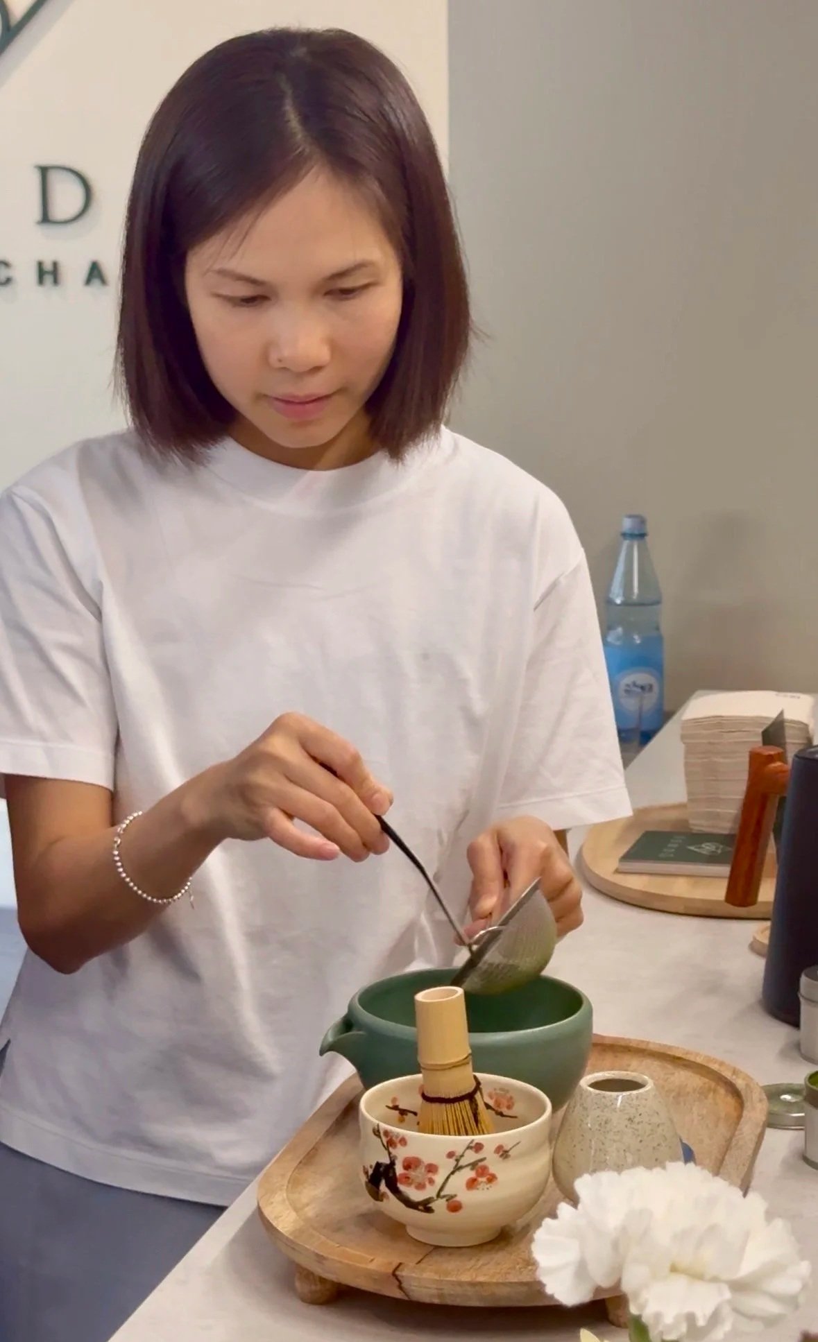 Vanessa bereitet Matcha zu und gibt grünes Matcha-Pulver mit einem Löffel in eine Schale.