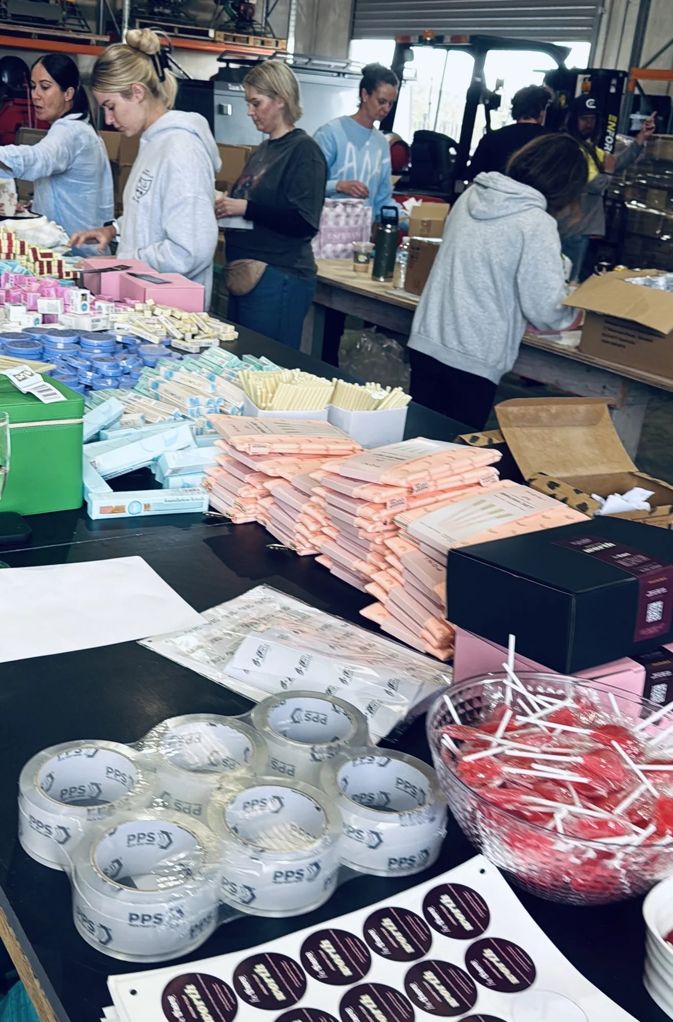 A volunteer at a packing station surrounded by items for the packs