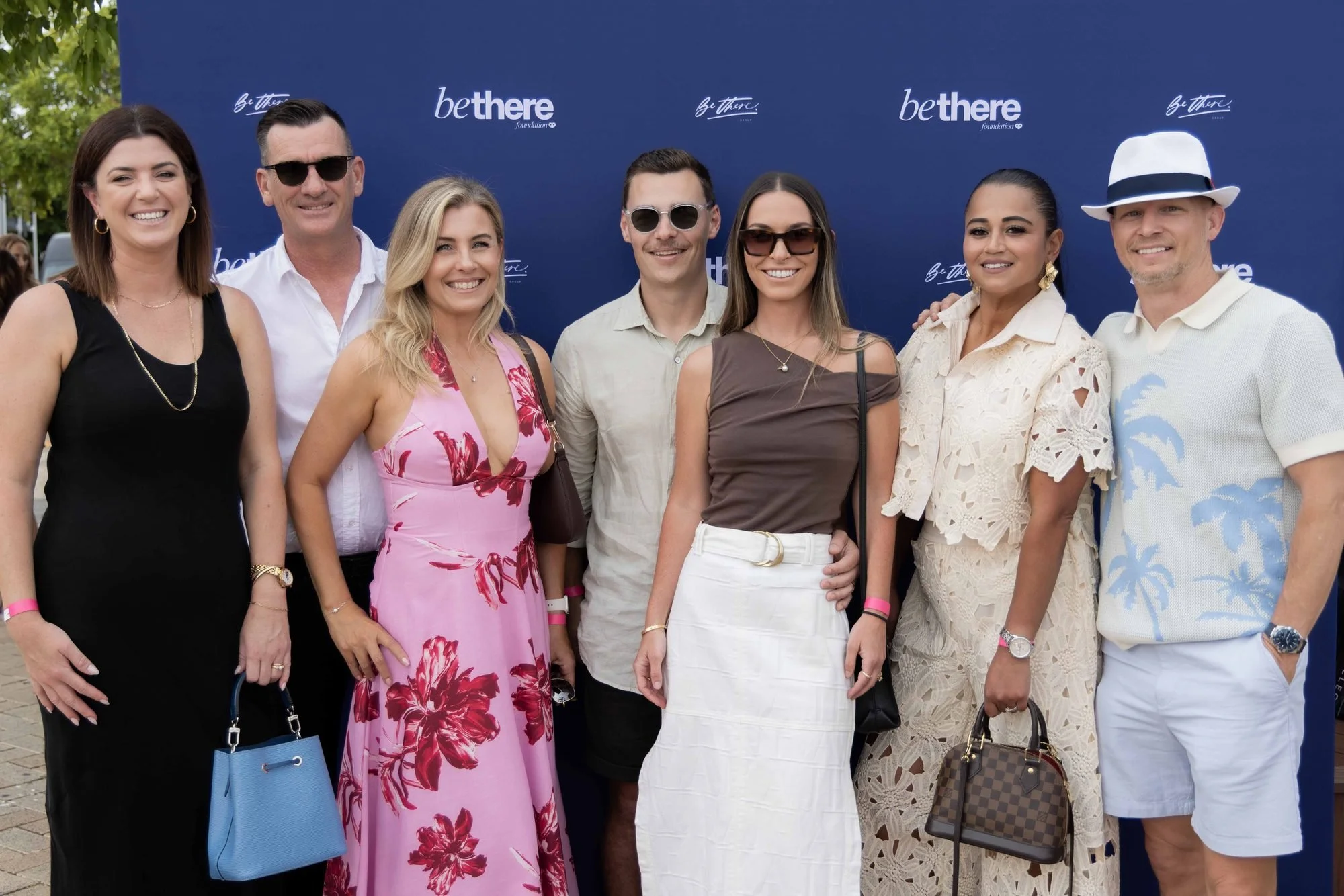 Guests at The Rolling Lunch 2026 in front of the Be There Foundation media wall at Sanctuary Cove