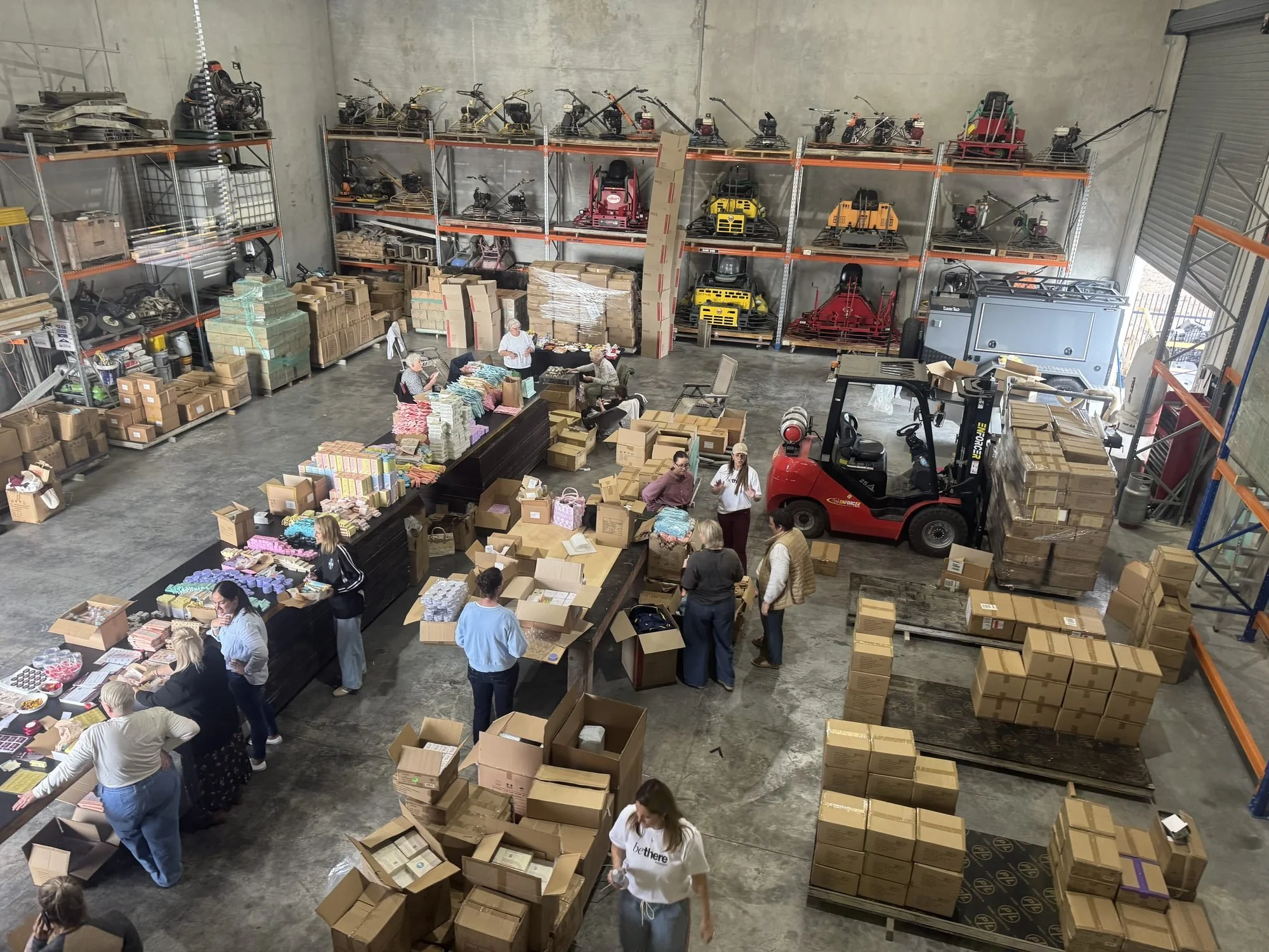 Volunteers at long packing tables in a warehouse at Be There Foundation's first Volunteer Packing Day