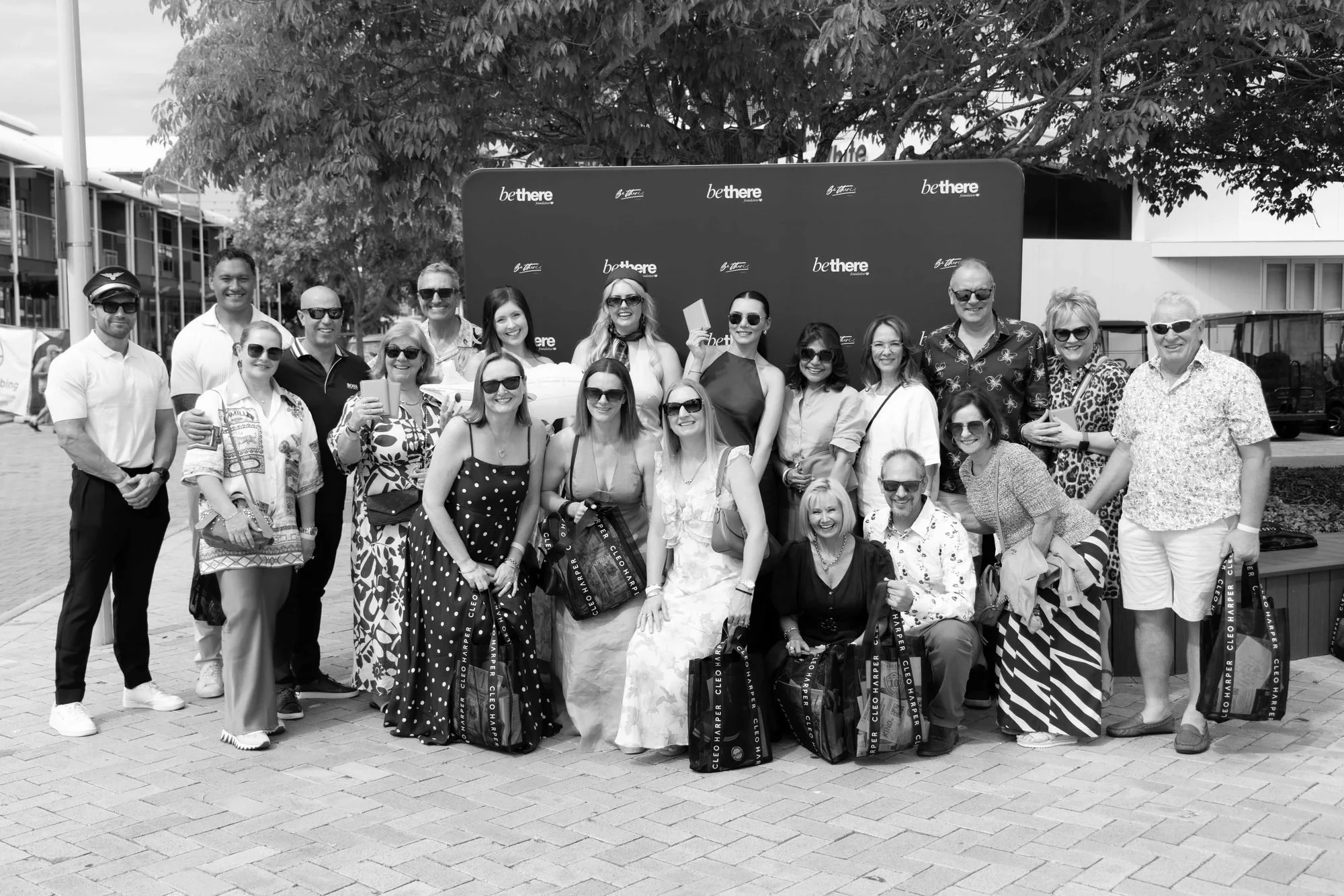 A large group of guests together at the Be There Foundation media wall at The Rolling Lunch 2026