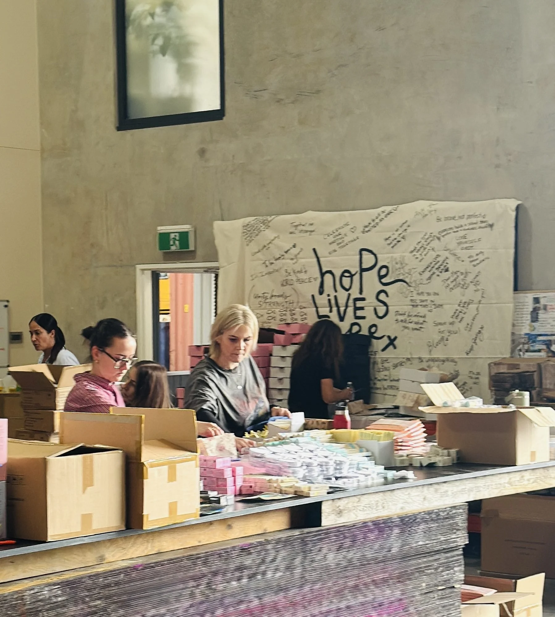 Volunteers working along the packing tables beneath a hand-signed banner